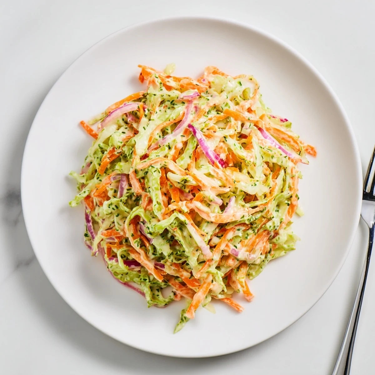 A close-up of creamy Coleslaw showing shredded cabbage and carrots tossed in tangy mayonnaise dressing.