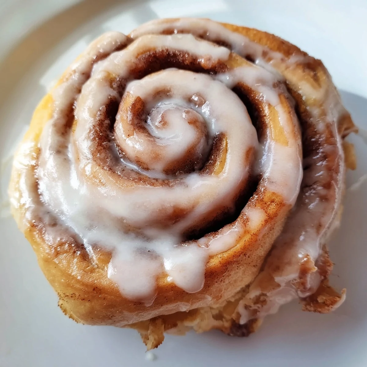 Homemade Cinnamon Rolls on a white plate, drizzled with sweet glaze and perfect for brunch.