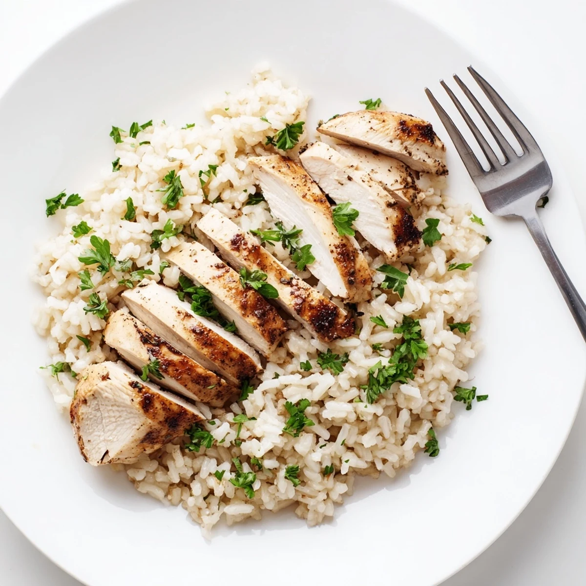 A close-up of tender sliced chicken resting on a bed of aromatic garlic butter rice, with a hint of steam rising from the fluffy grains.