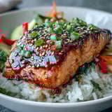 Colorful julienned carrots, cucumber, and bell pepper add crunch to this healthy Asian-Inspired Salmon Bowl, served with lime wedges.