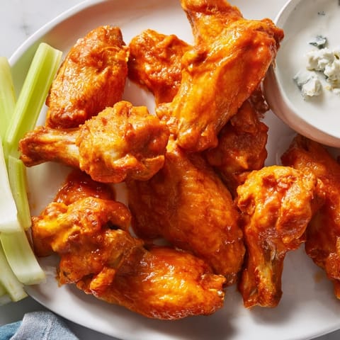 Crispy fried Buffalo Wings piled high, ready for game day with celery sticks and creamy dip.
