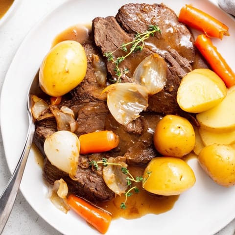 Fork-tender Beef Pot Roast with carrots and potatoes served in a rich savory gravy.