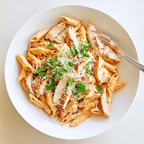 Sliced seared chicken rests atop penne noodles, blanketed in a glossy, sweet-smoky honey chipotle sauce, with steam rising from the dish.