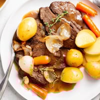 Fork-tender Beef Pot Roast with carrots and potatoes served in a rich savory gravy.