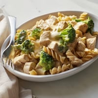 Golden brown chicken pieces and bright green broccoli florets coated in a creamy cheddar cheese sauce for the Chicken Broccoli Cheddar Pasta.