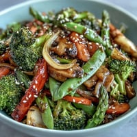 A vibrant bowl of Ginger Stir-Fried Vegetables with crisp broccoli, carrots, and snap peas glistening in savory soy sauce.  
